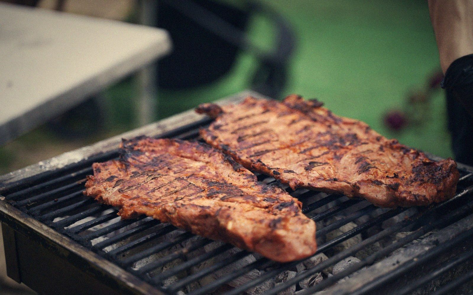 Two grilled steaks with charred grate marks sitting on an outdoor barbecue grill