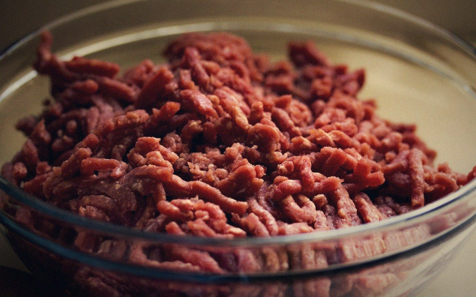 Raw ground beef piled in a clear glass bowl