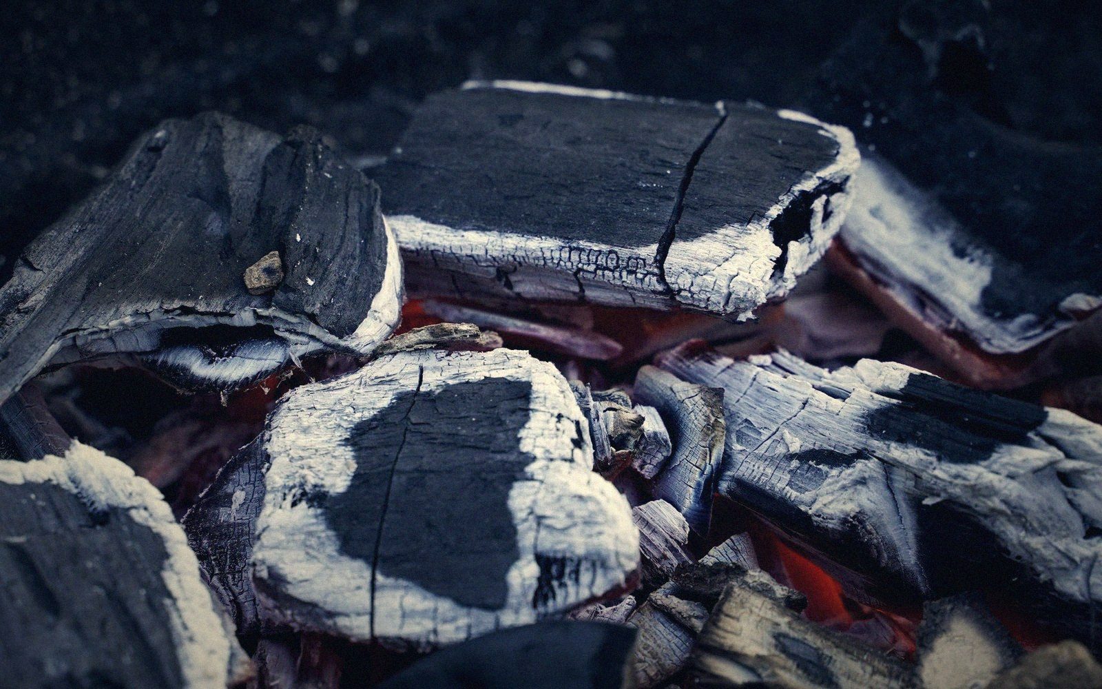 Close-up of glowing charcoal briquettes covered in white ash with red embers beneath