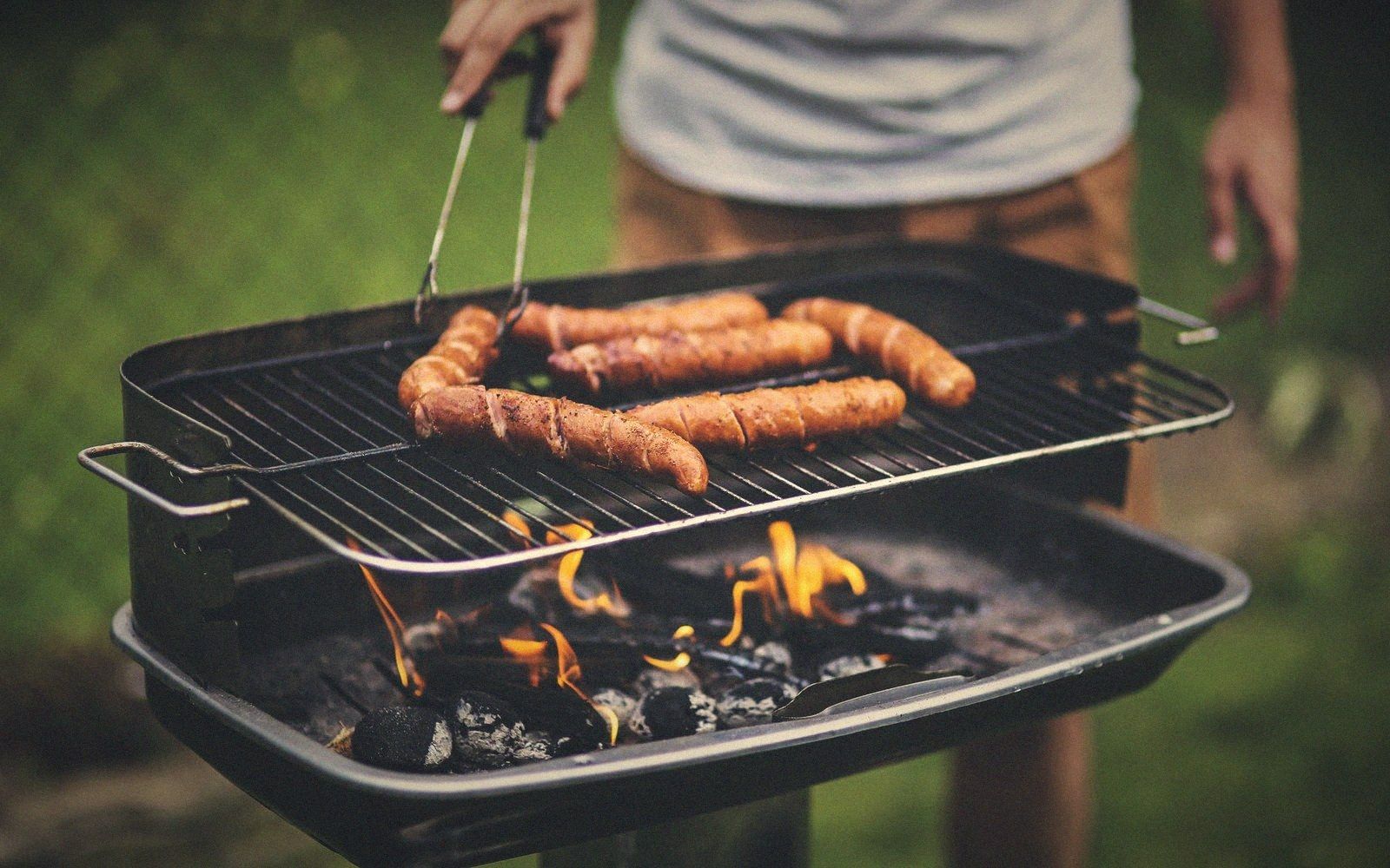 A cook laying a two-zone charcoal bed with tongs