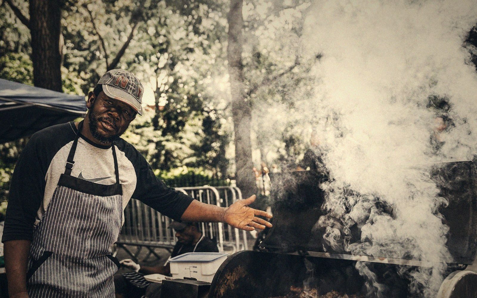 Smoke rising off a grill with somebody watching it